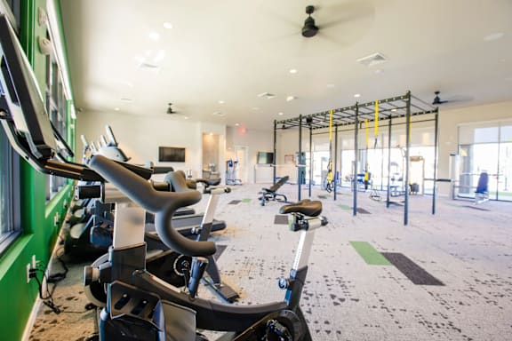 A gym with a green wall and a variety of exercise equipment.