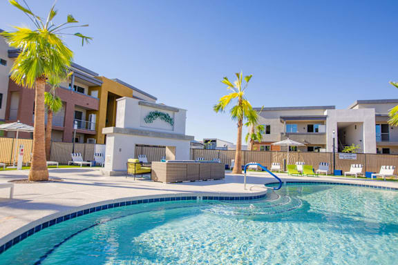 A pool in front of a building with palm trees.