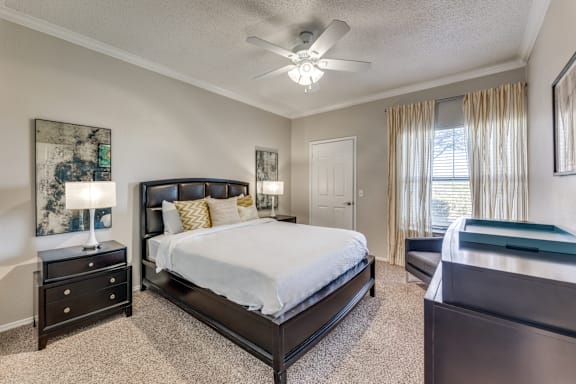 A bedroom with a large bed and a ceiling fan.