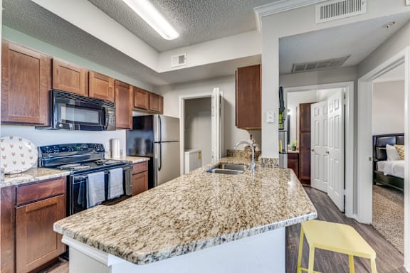 A kitchen with a granite counter top and a yellow stool.