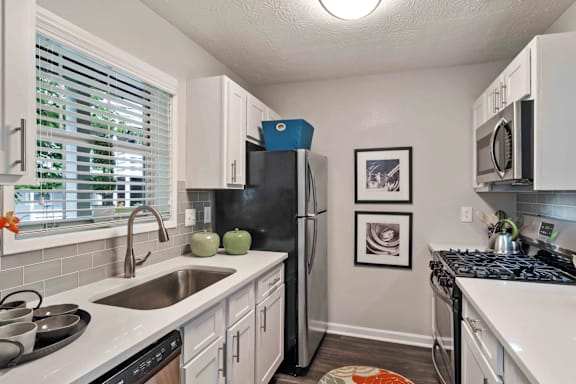 A kitchen with a black fridge and white cabinets.
