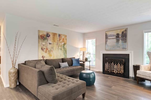 A living room with a grey couch, a blue ottoman, and a fireplace.