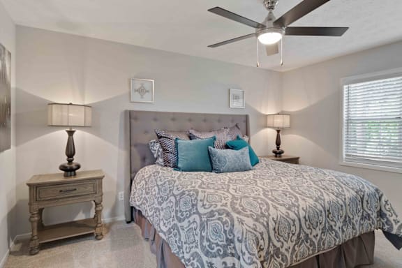 A bedroom with a bed, nightstand, and ceiling fan.