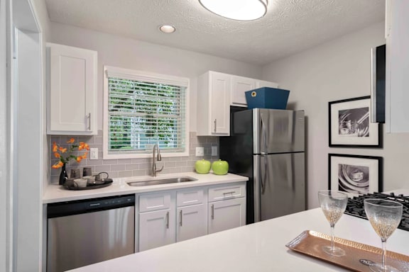 A kitchen with white cabinets and a stainless steel refrigerator.