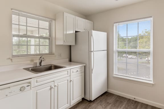 a kitchen with white cabinets and a sink and a refrigerator