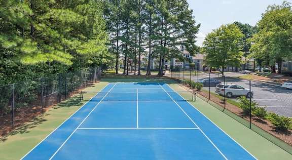 a blue and green tennis court with trees in the background