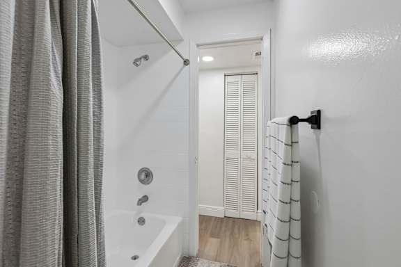 A white bathroom with a shower curtain and a white door.