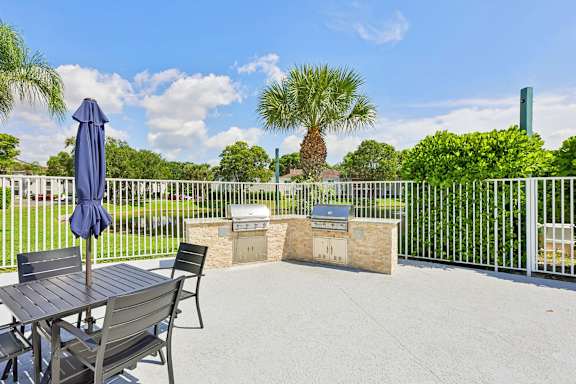 A patio with a table and chairs and a blue umbrella.