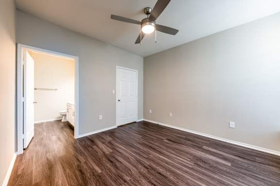 A room with a ceiling fan and wood flooring.