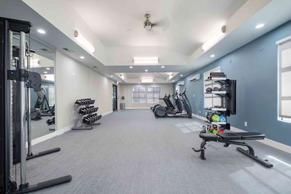 A spacious gym with a variety of equipment including treadmills, stationary bikes, and weight machines.
