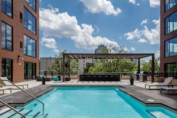 A swimming pool surrounded by a patio area with lounge chairs and umbrellas.