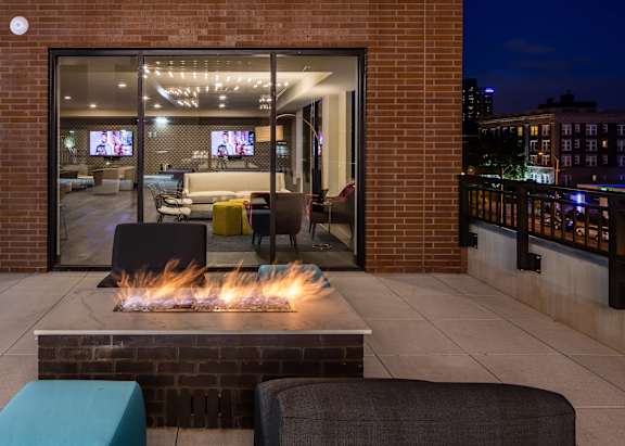 A modern patio with a fire pit and seating area.