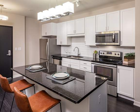 A modern kitchen with a black granite countertop and white cabinets.