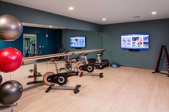 A gym with exercise equipment and a television screen.