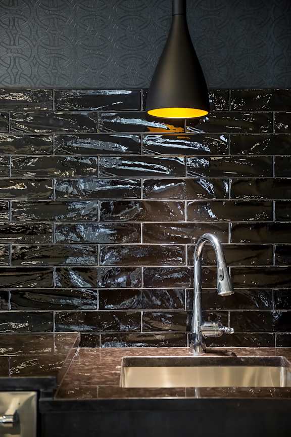 A black lamp shade hangs over a sink in a darkly lit bathroom.
