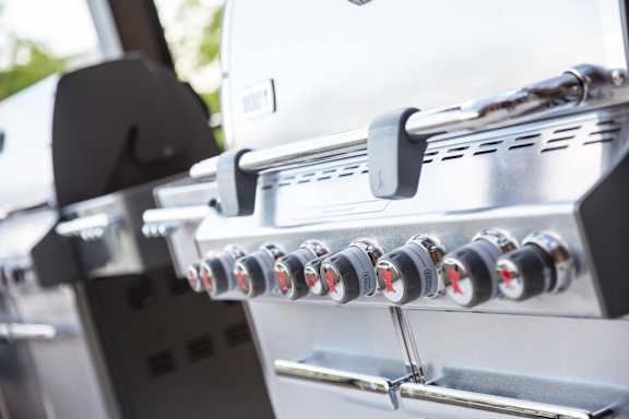 A close up of a gas grill with knobs and a handle.