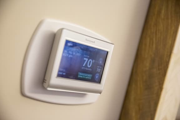 A wall-mounted thermostat displays a temperature of 70 degrees.