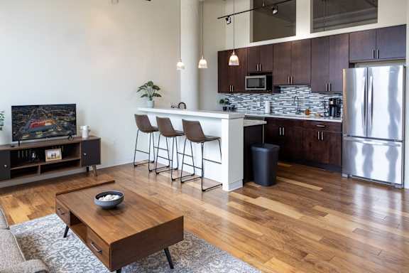 A modern kitchen with a wooden floor and a white wall.