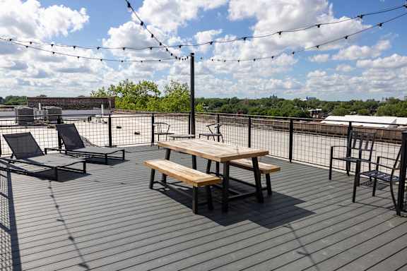 A wooden table and chairs are set up on a deck with a view of the city.