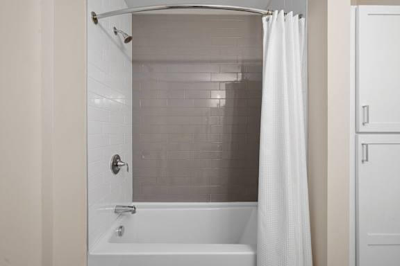 A white bathroom with a white tub and shower curtain.