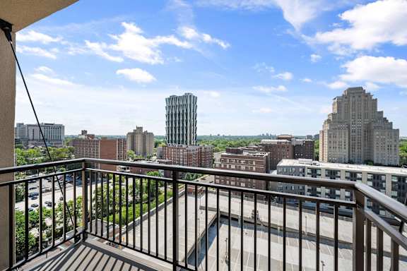 A balcony overlooks a cityscape with buildings and a clear sky.