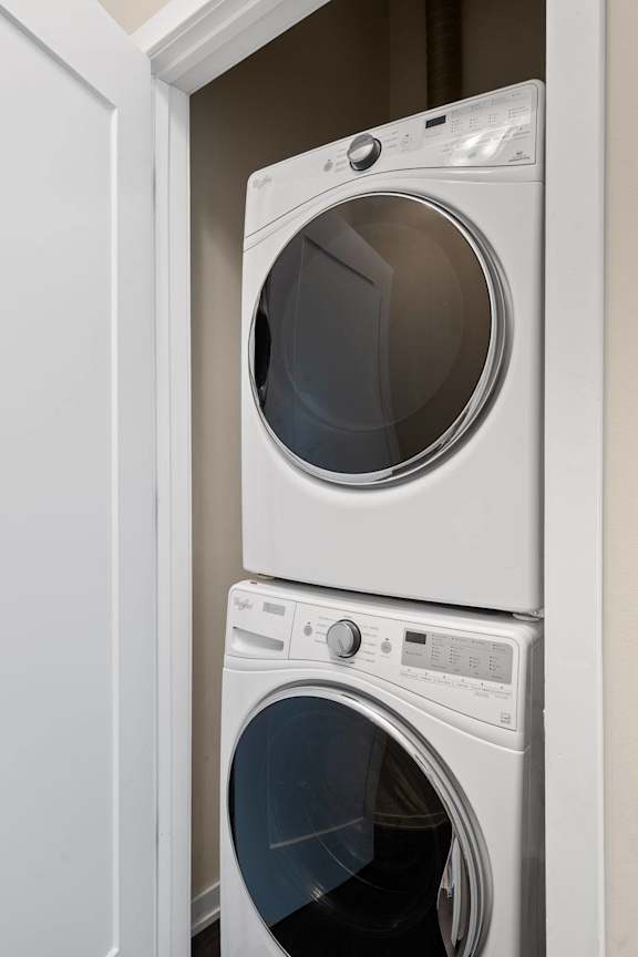 Two white front loading washing machines in a cabinet.