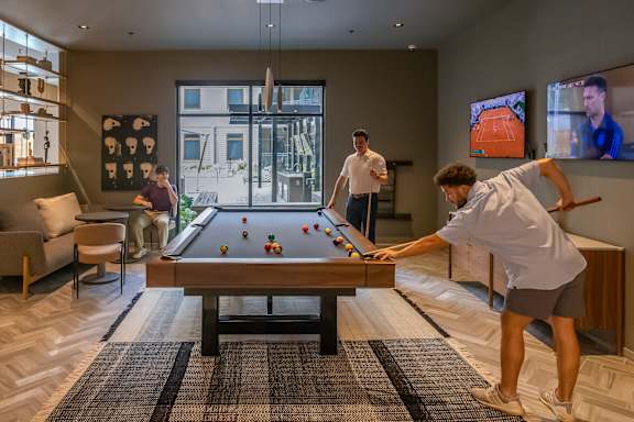 Two men playing pool in a room with a pool table.