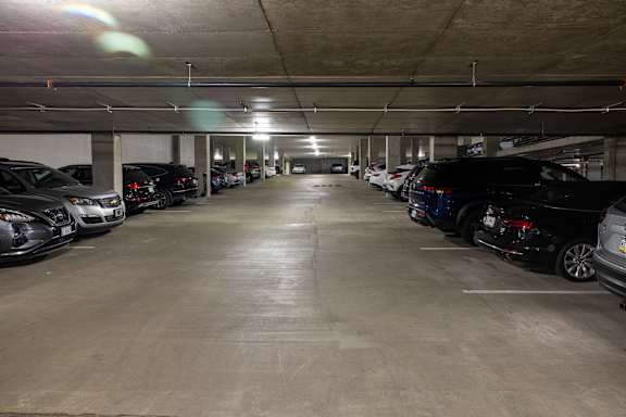 A parking garage with cars parked on both sides of the aisle.