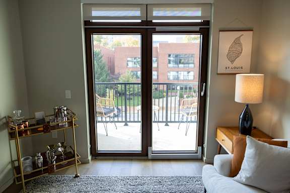 A living room with a couch, a lamp, and a view of a patio through the sliding glass doors.