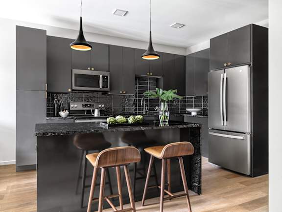 A modern kitchen with a black countertop and stainless steel appliances.