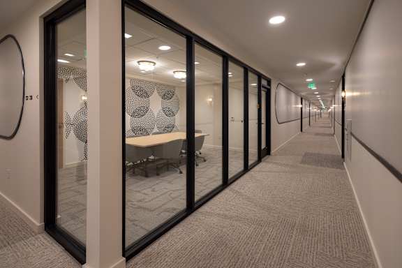 A long hallway with glass doors and carpeted floors.