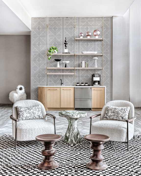 A living room with a patterned carpet and a glass table.