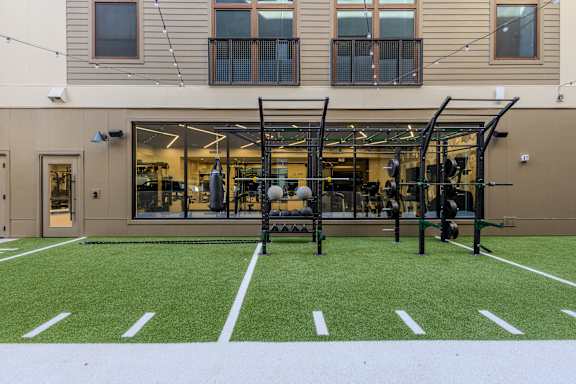 A gym with a green artificial turf in front of a building.