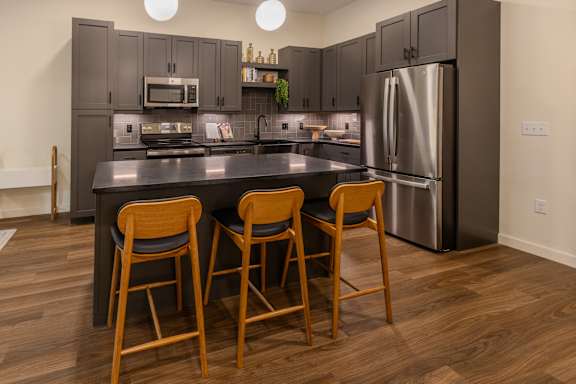 a kitchen with stainless steel appliances and a counter with three chairs