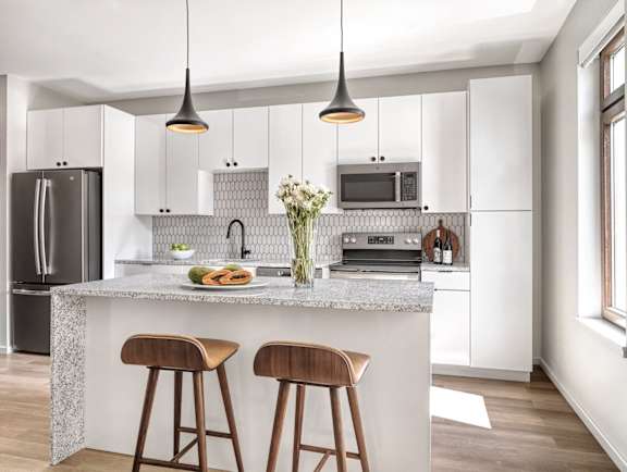 A modern kitchen with a granite countertop and wooden bar stools.