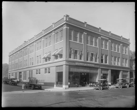 a black and white photo of a building with cars in front of it