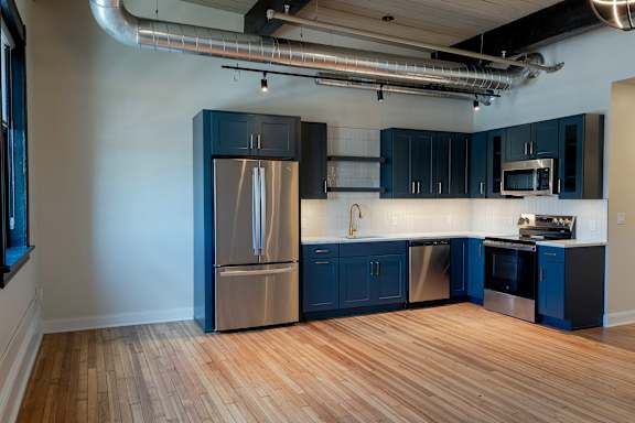 A kitchen with dark blue cabinets and stainless steel appliances.