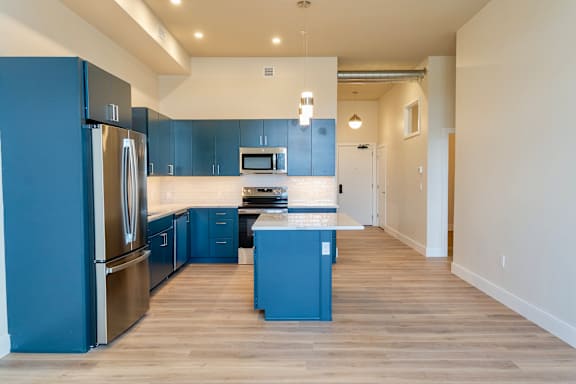 A kitchen with blue cabinets and stainless steel appliances.
