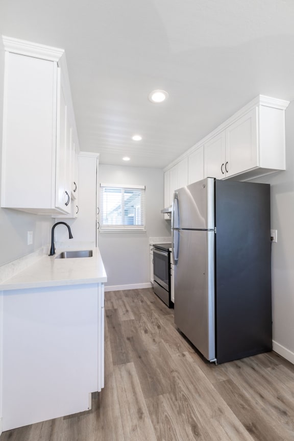 a renovated kitchen with white cabinets and a stainless steel refrigerator