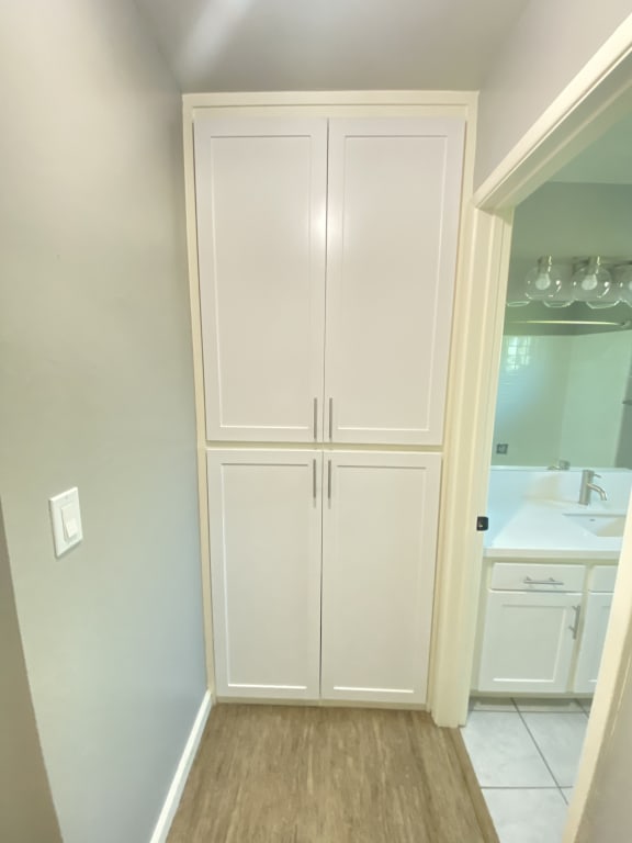 a closet with white cabinets and a sink in a bathroom