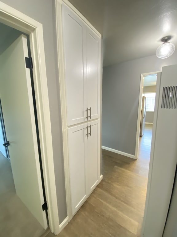 a large white cabinet in the middle of a hallway with a door to a room