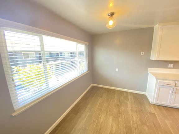 an empty kitchen with large window and wood flooring