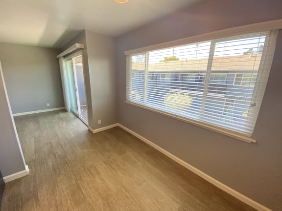 an empty living room with a large window and wooden floors