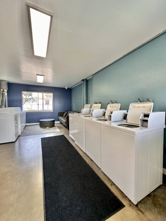 a laundry room with white machines and a black rug at The Chase Apartment Homes, Oakland, CA 94606