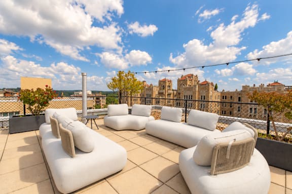 A rooftop patio with white couches and a view of the city.