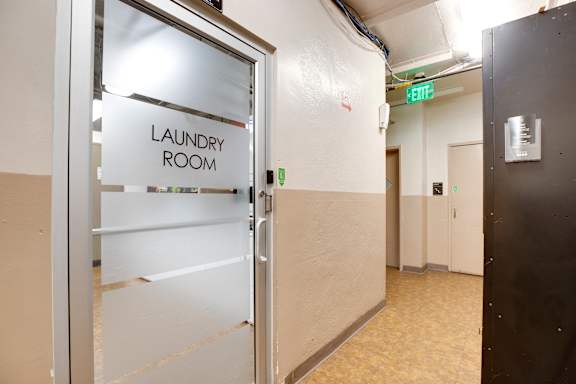 A laundry room sign is on a glass door.