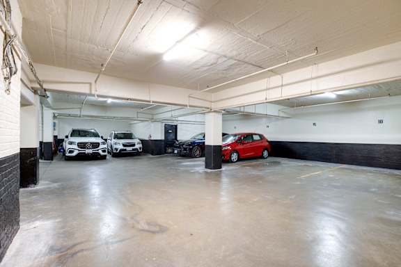 A parking garage with a red car in the foreground.