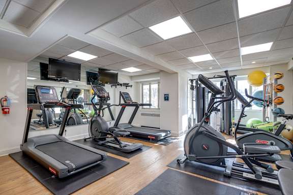A gym with treadmills, elliptical machines, and other exercise equipment.
