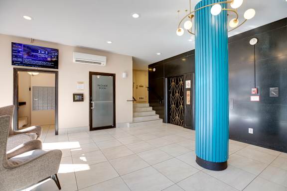 A blue column stands in a white hallway with a chair and a TV.