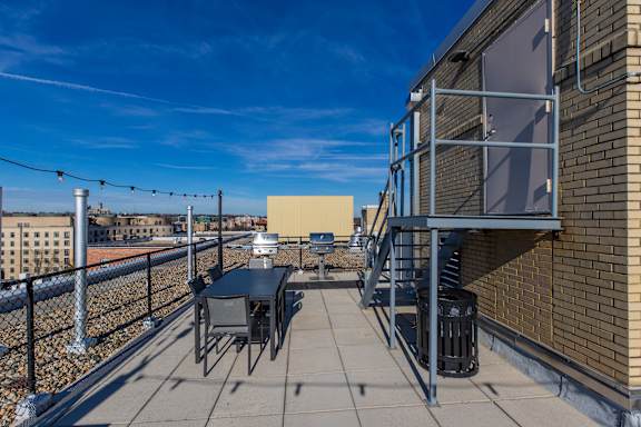A rooftop patio with a table and chairs.